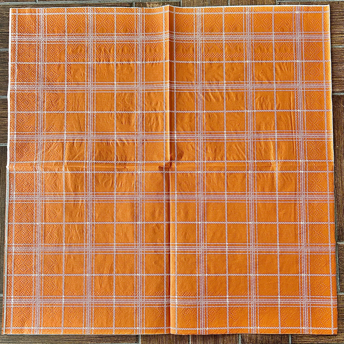 Orange plaid fabric on a wooden background