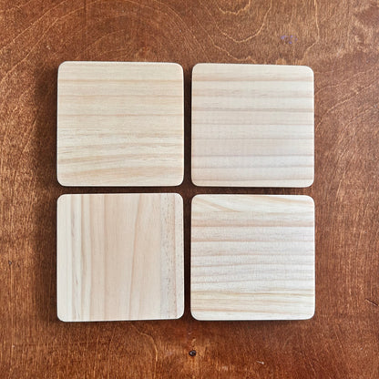 Four square wooden coasters on a wooden surface