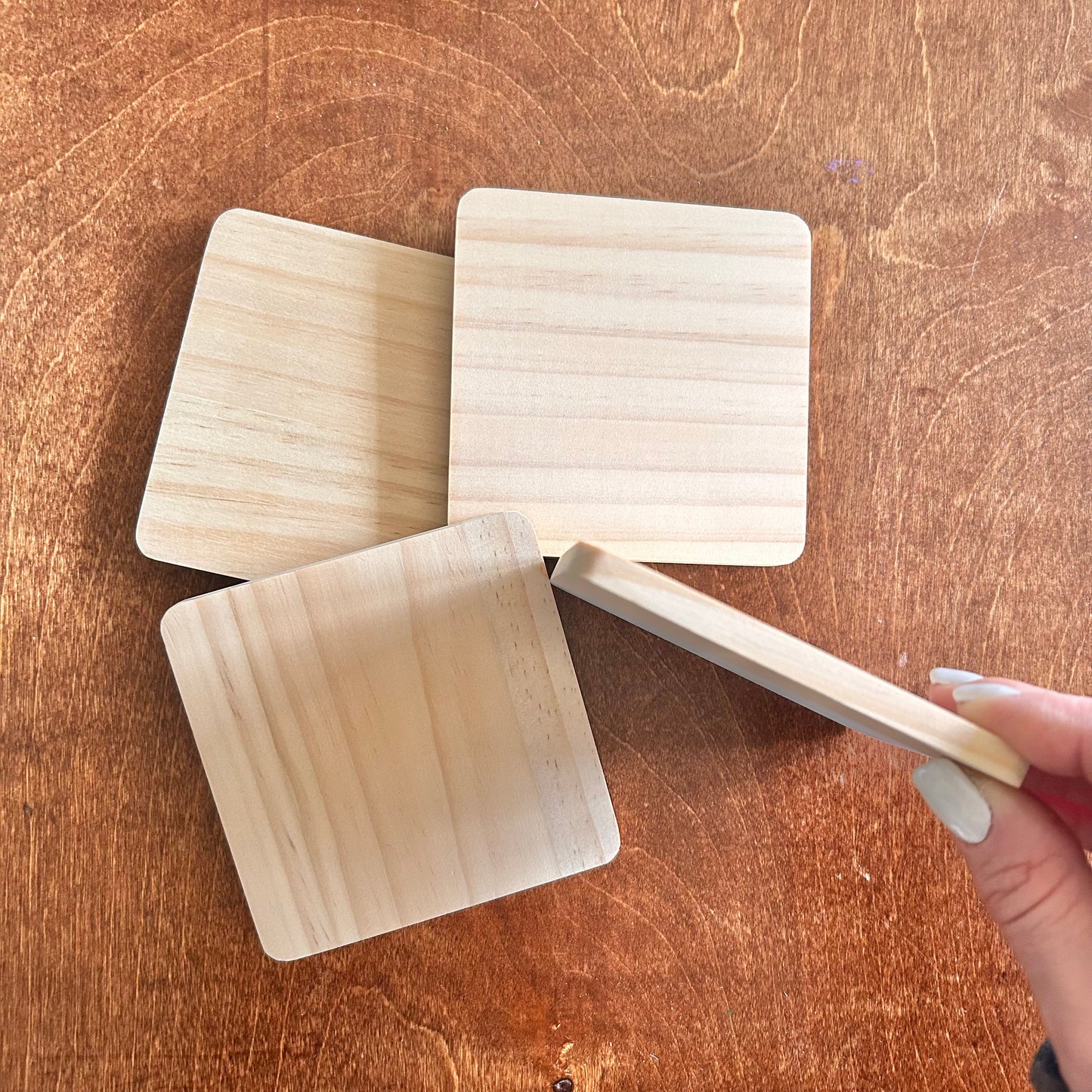 Wooden coasters where 3 are laying flat and one is on it's side on a wooden surface