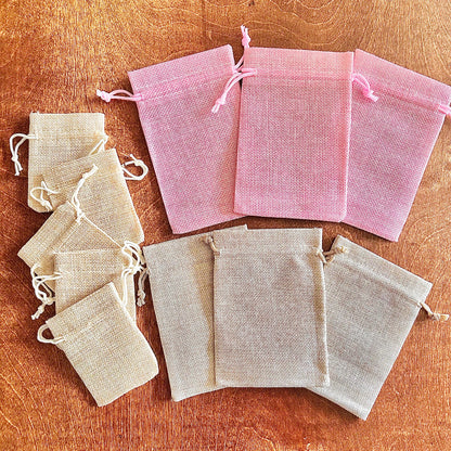 Sets of pink and beige burlap drawstring bags on a wooden surface