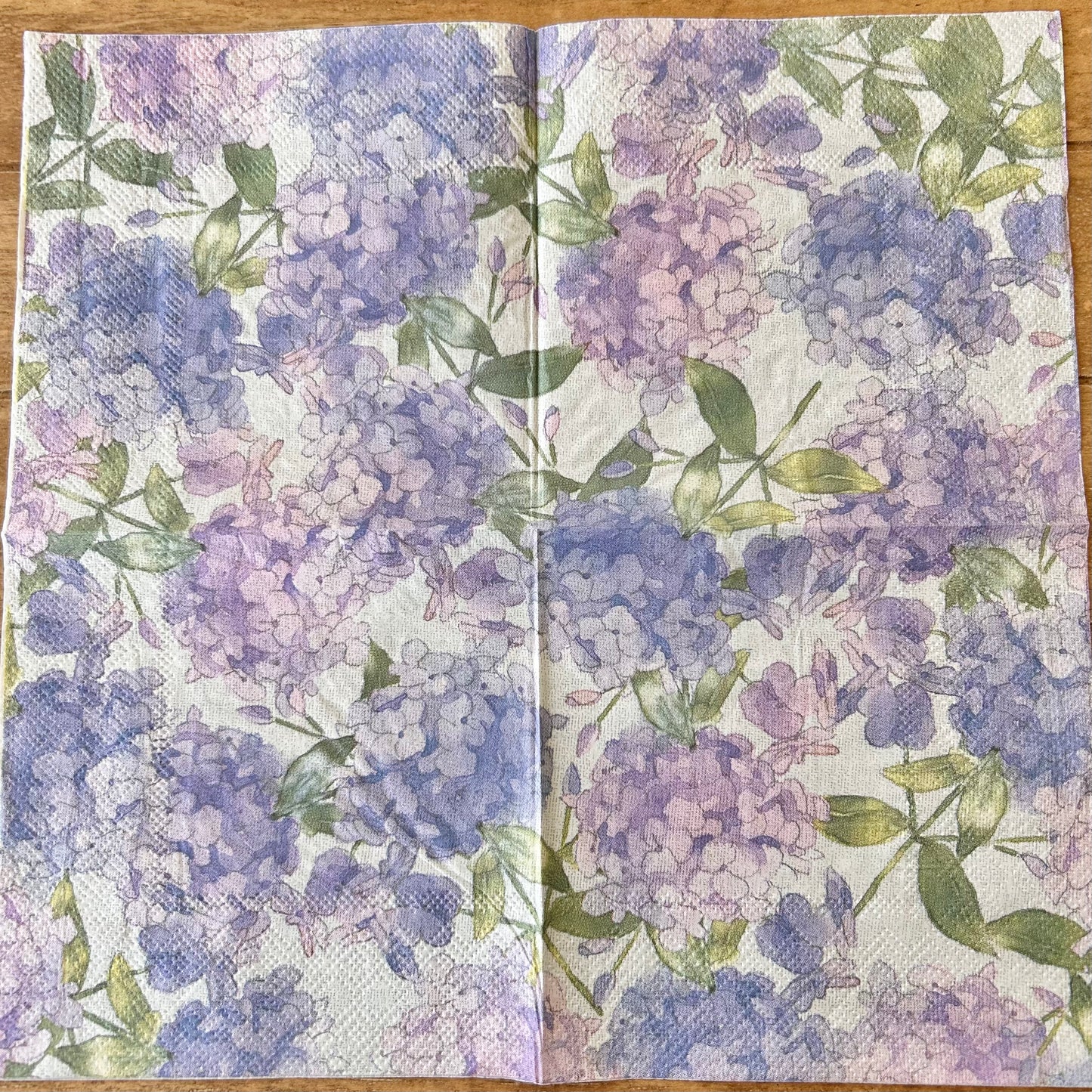 Floral patterned napkin with purple and green flowers on a wooden surface