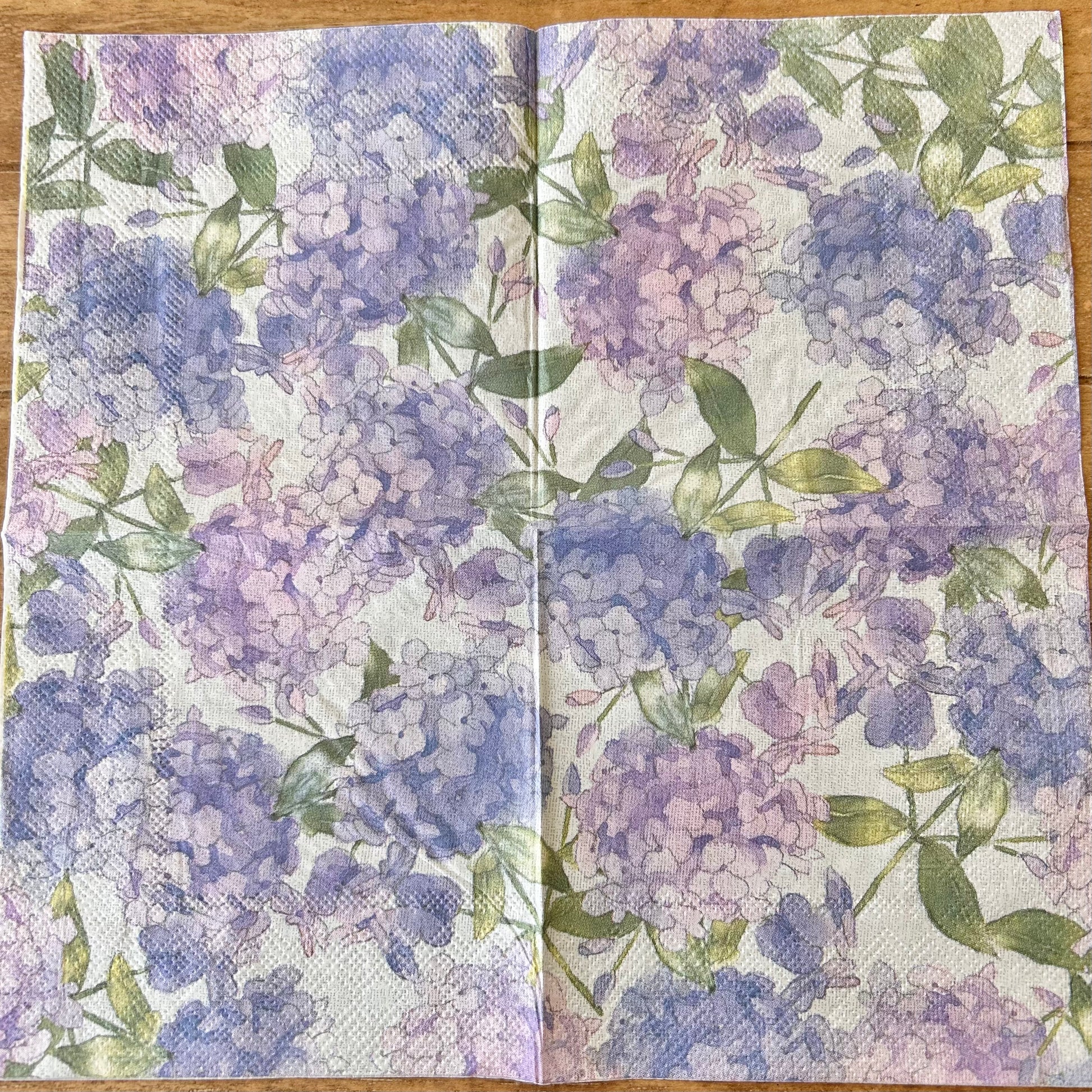 Floral patterned napkin with purple and green flowers on a wooden surface