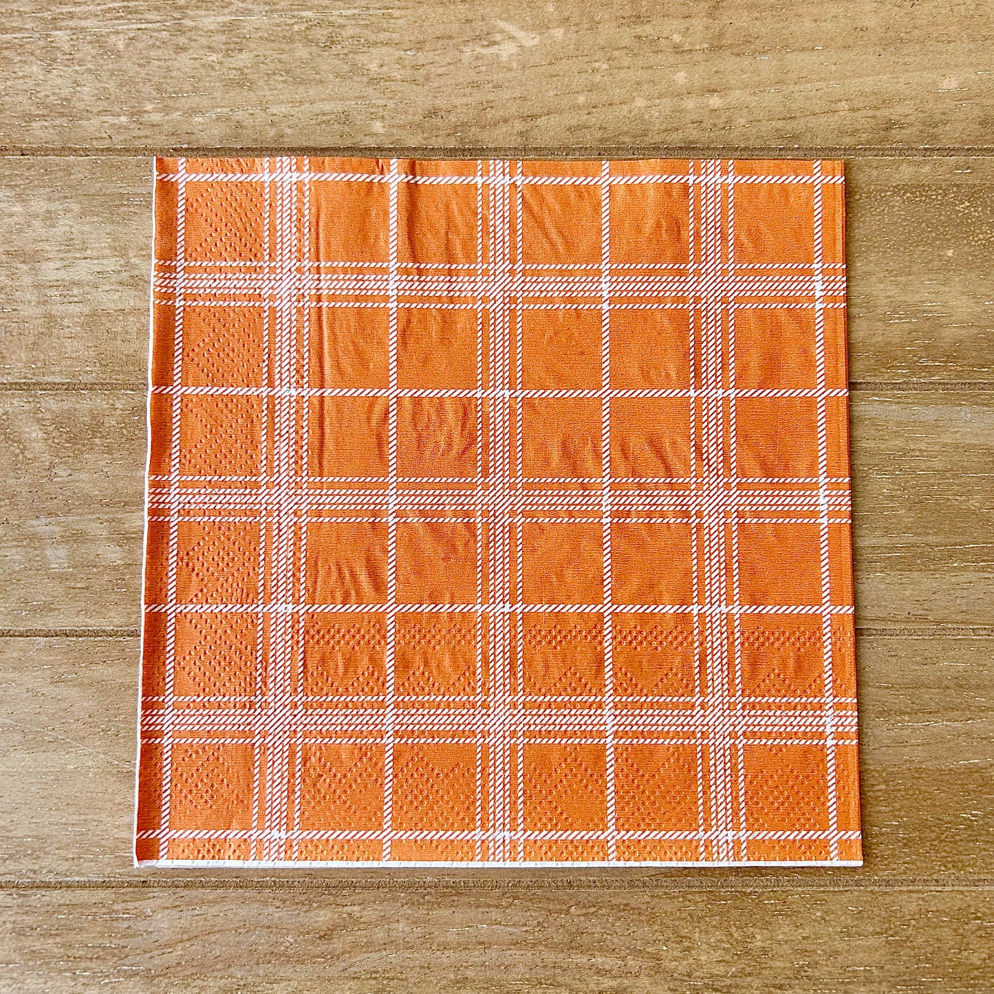 Plaid fabric with orange and white pattern on a wooden surface