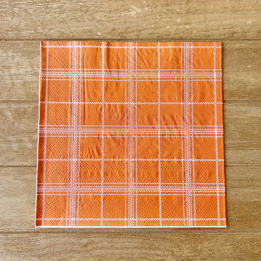 Plaid fabric with orange and white pattern on a wooden surface
