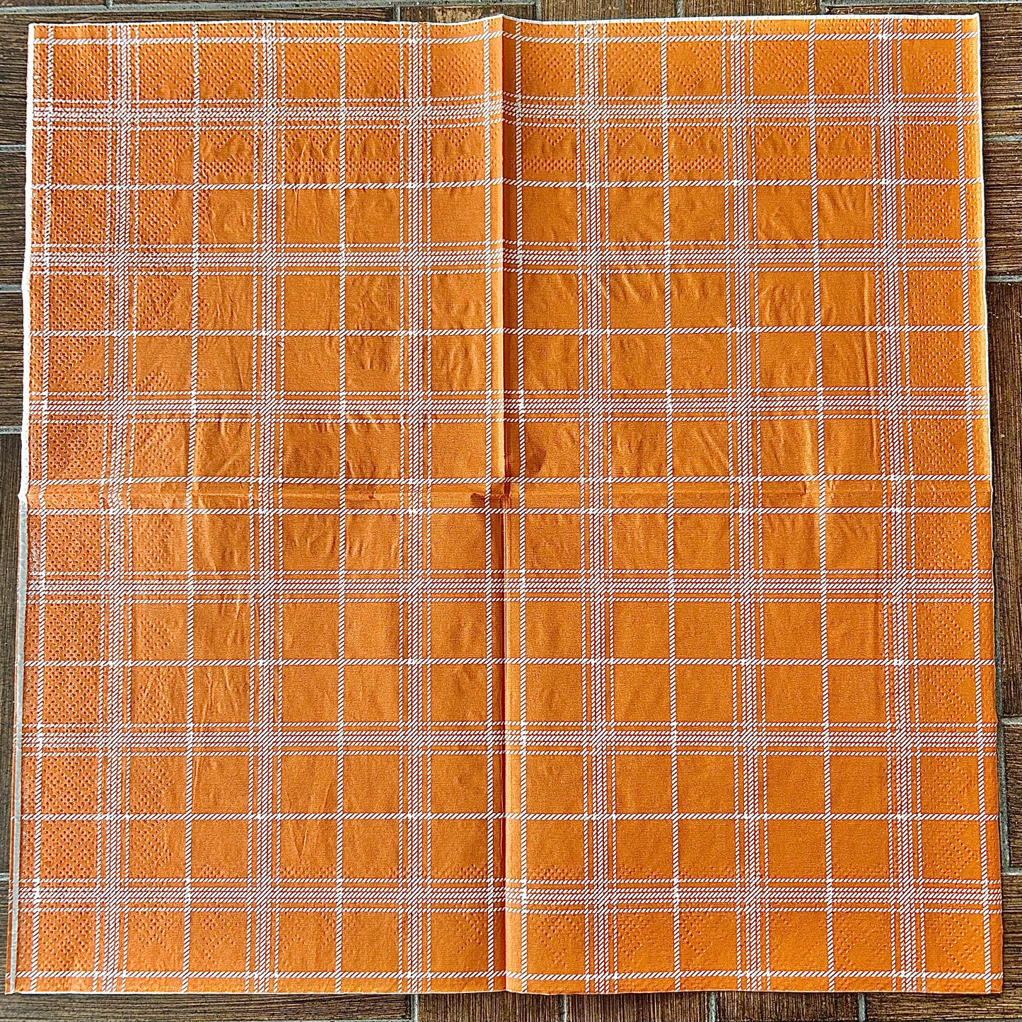 Orange plaid fabric on a wooden background