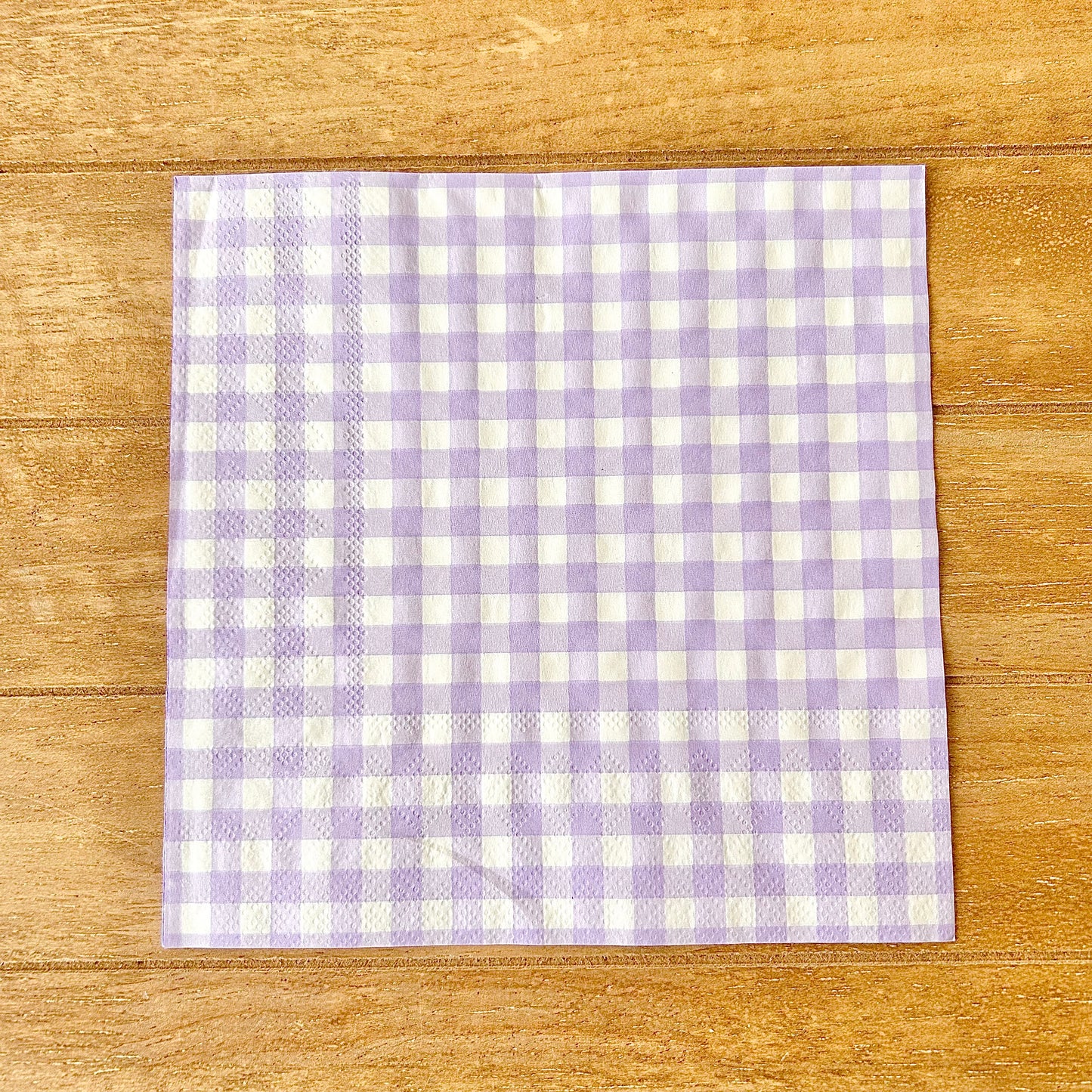Purple and white checkered napkin on a wooden surface