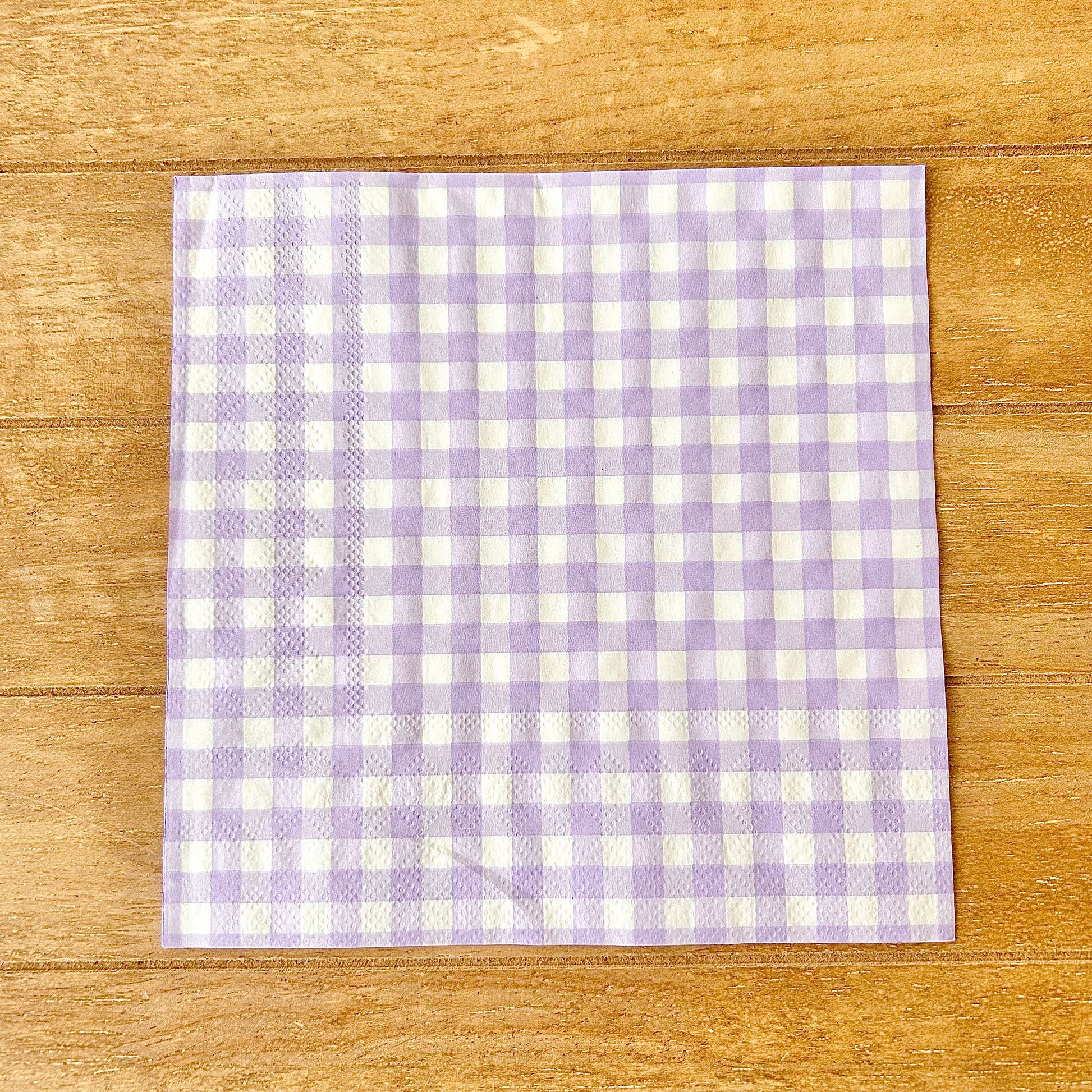 Purple and white checkered napkin on a wooden surface