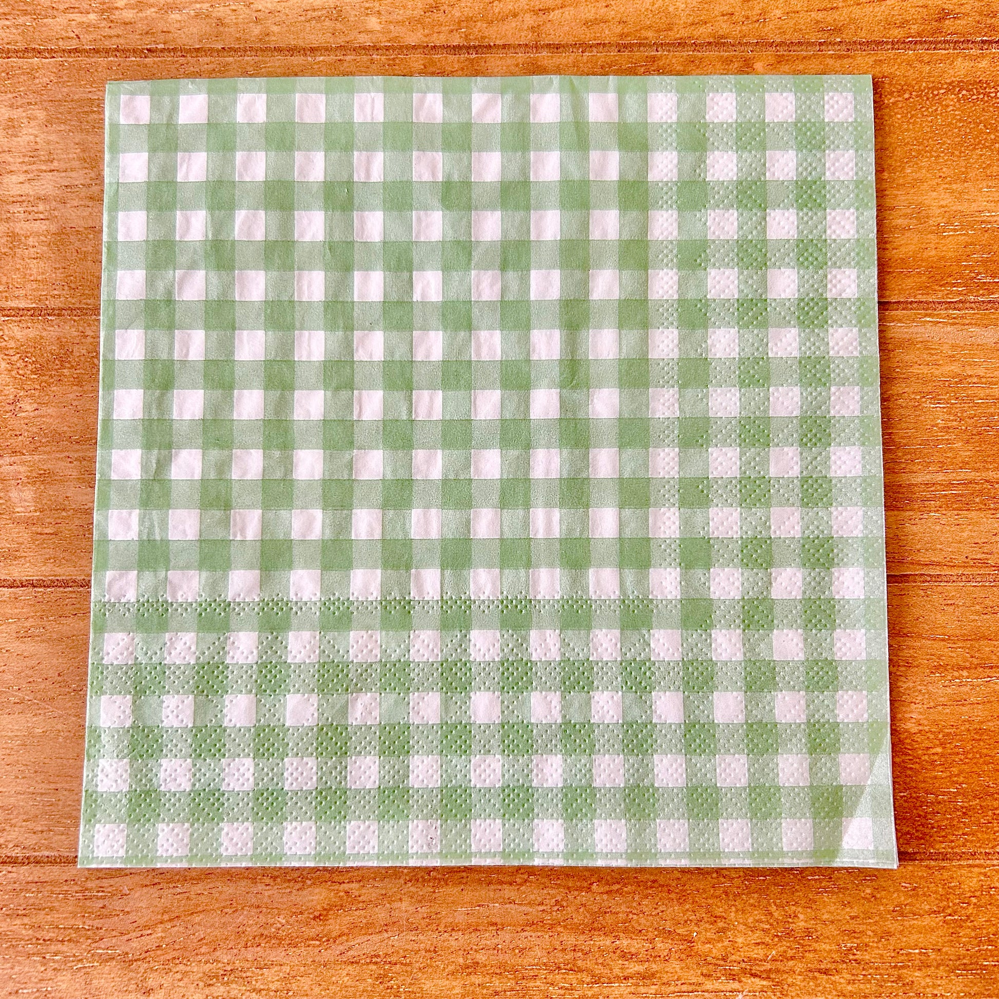 Green and white checkered napkin on a wooden surface
