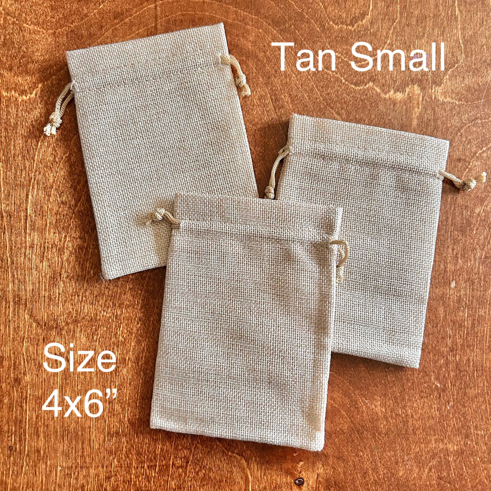 Three tan fabric drawstring bags on a wooden surface with text indicating size and color.