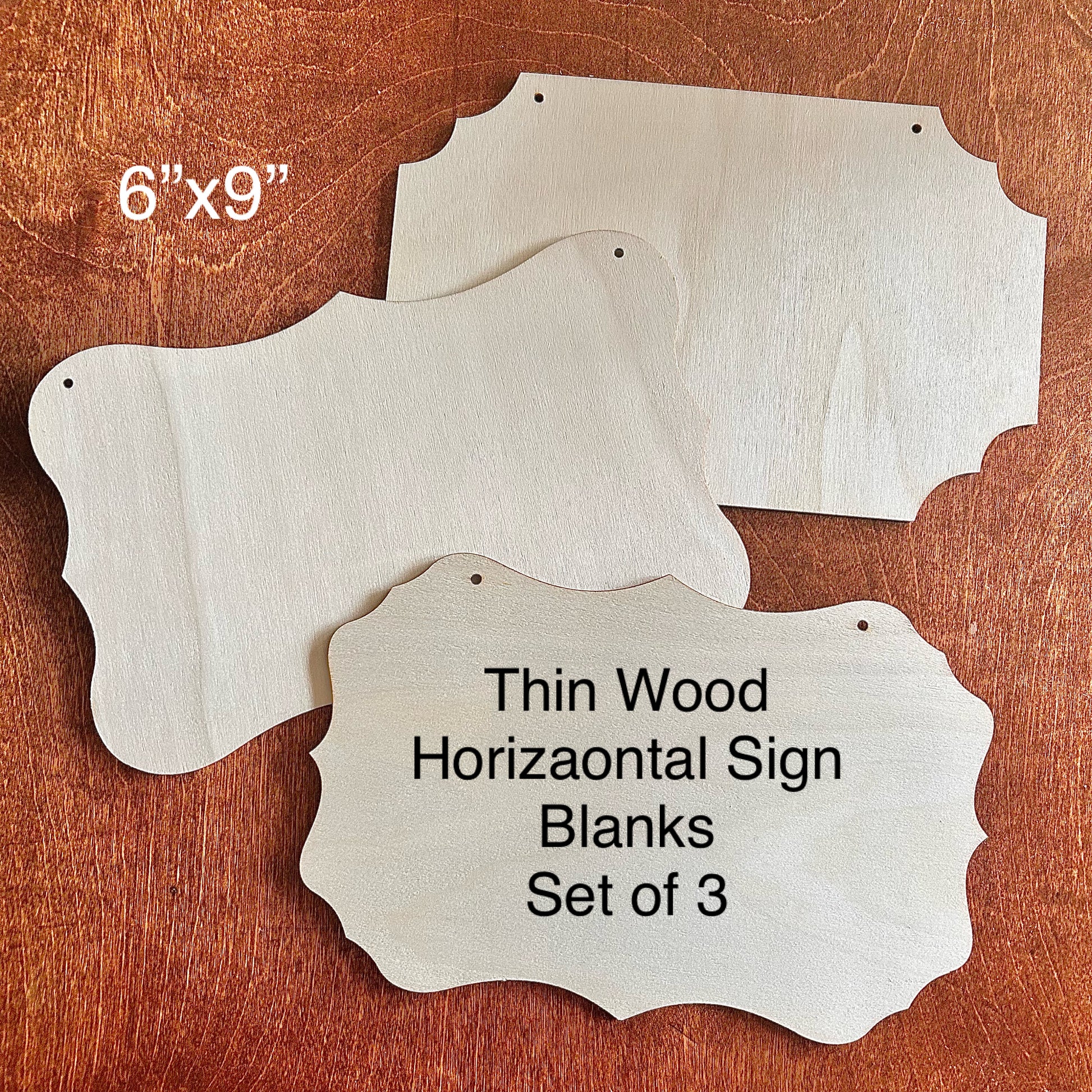 Three thin wood horizontal sign blanks on a wooden surface with text indicating size and description.